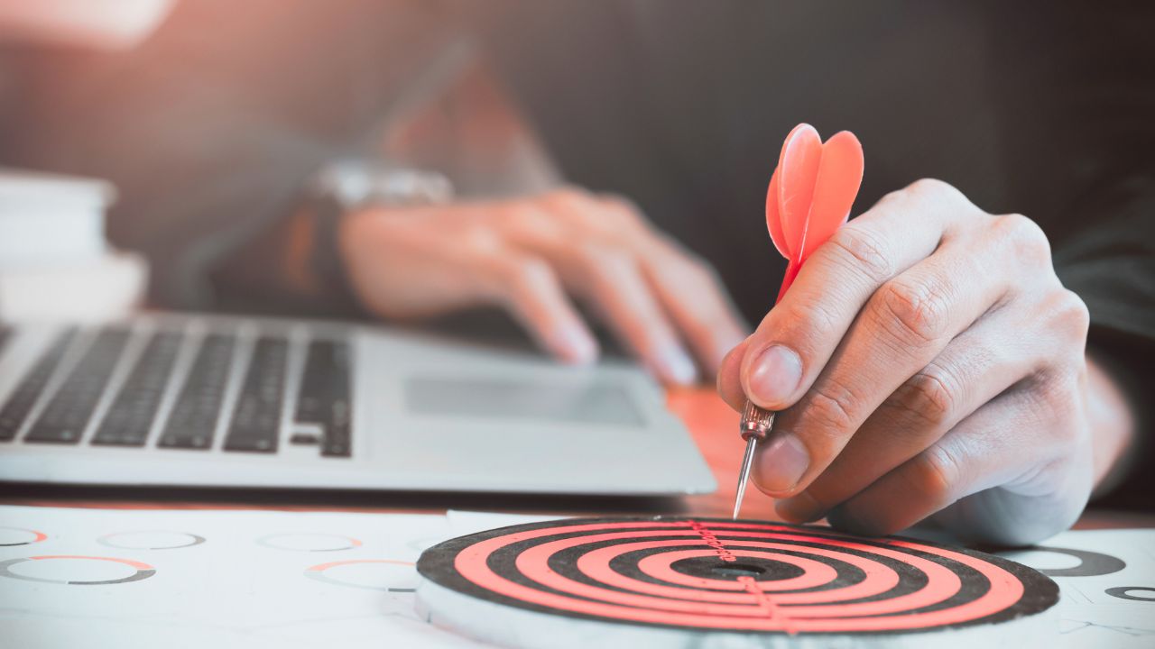 Imagem de um alvo ao lado de um computador simulando o objetivo a ser alcançado com o ataque cibernético.